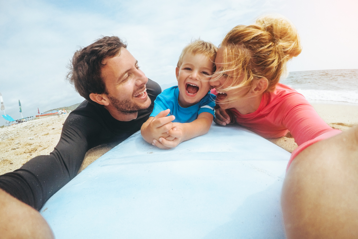 Lachende Surferfamilie am Strand