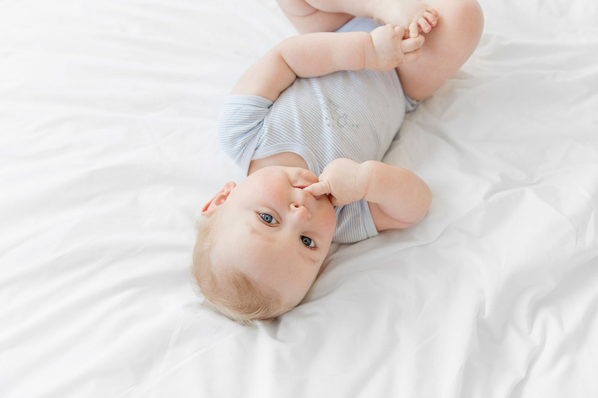 Babyfotos: Baby mit blauen Augen auf weißer Decke