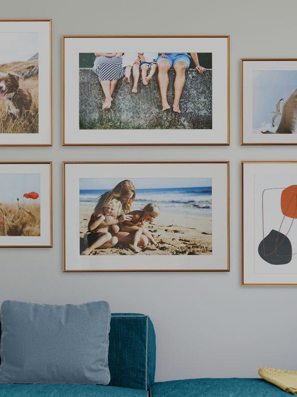 Acht Bilder hängen an der Wand über einem Sofa