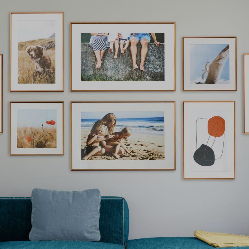 Acht Bilder hängen an der Wand über einem Sofa