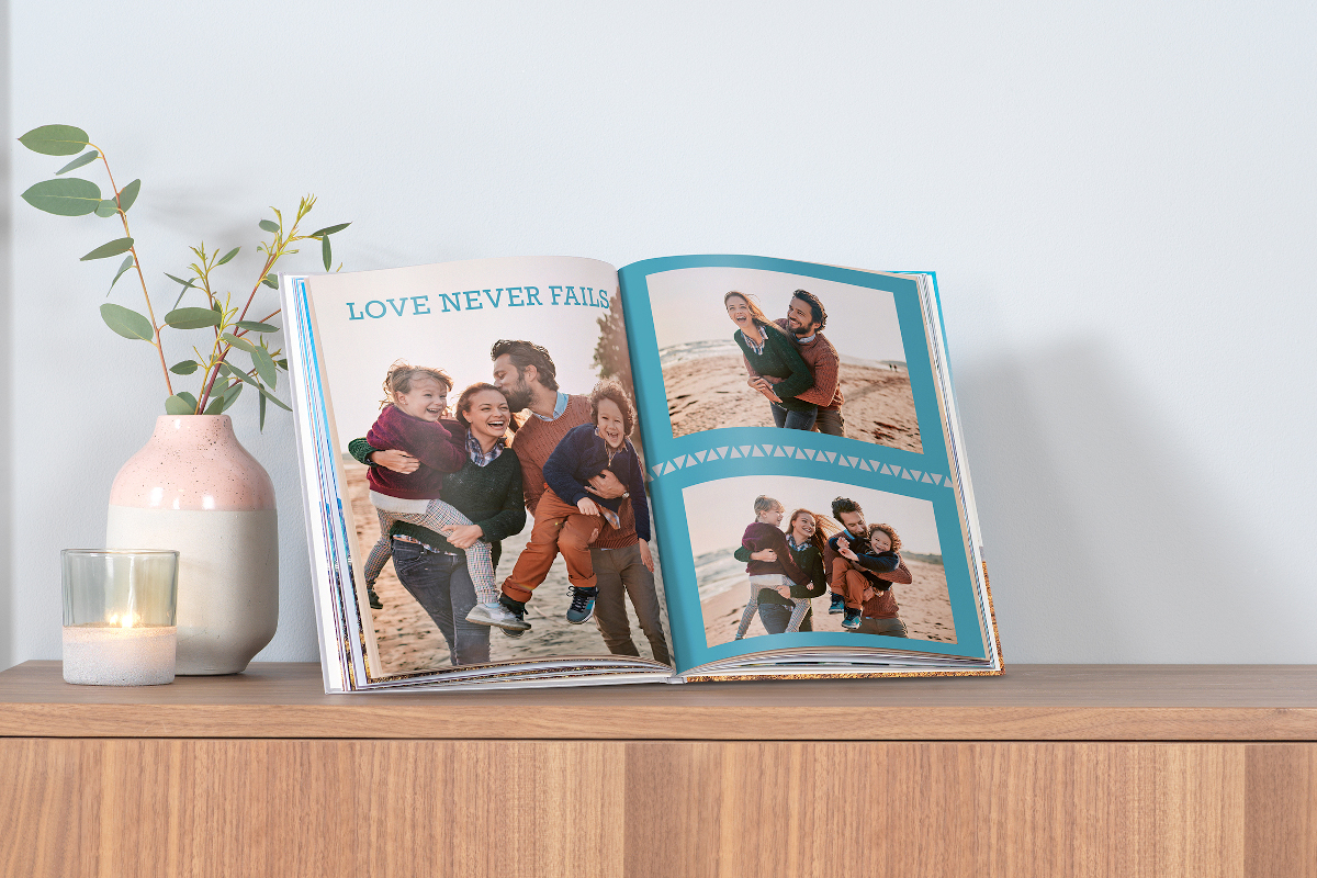 Pixum Fotobuch mit Familienbilder vom Urlaub liegt auf der Komode