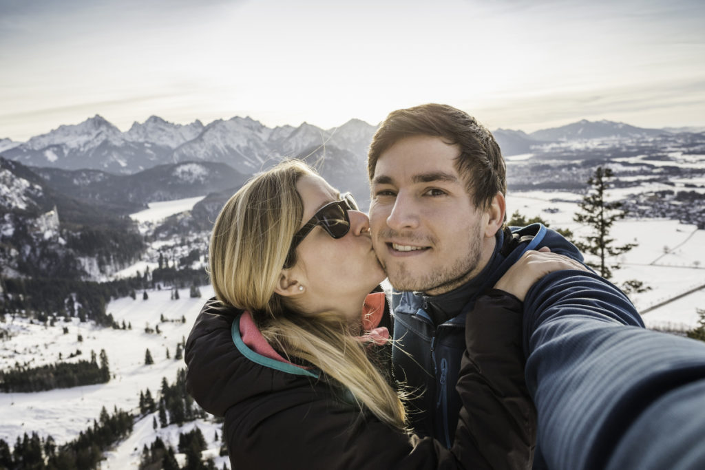 Paar macht Selfie beim Wandern in den verschneiten Alpen